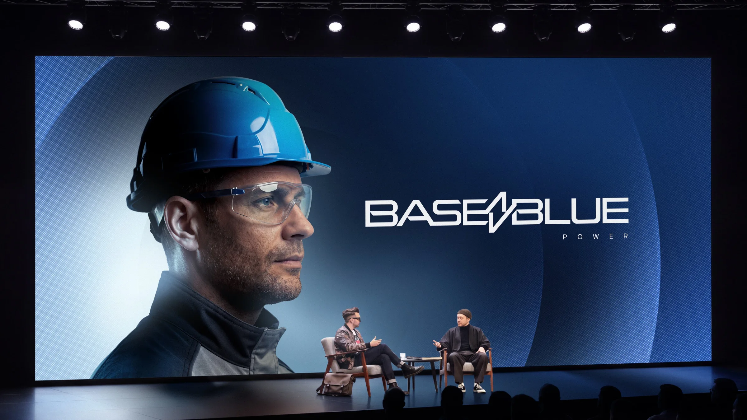 Escenario de conferencia de BaseBlue Power con un ingeniero con casco en pantalla